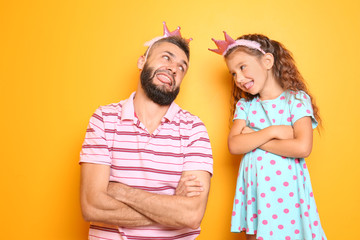 Funny portrait of father and his little daughter on color background