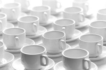 White cups for tea  stacked in line on table with tablecloth for