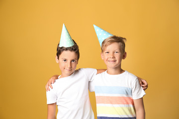 Cute little boys in Birthday hats on color background