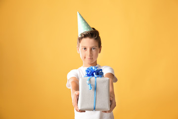 Cute little boy with Birthday gift on color background