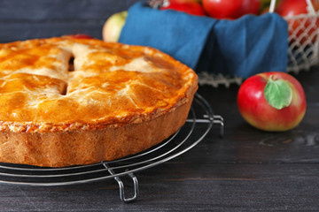 Cooling rack with delicious apple pie on wooden table, closeup