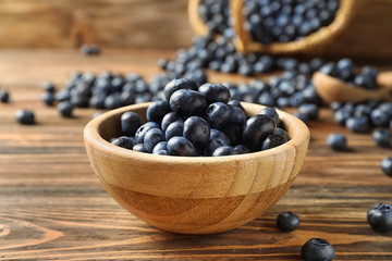 Bowl with ripe blueberries on wooden table