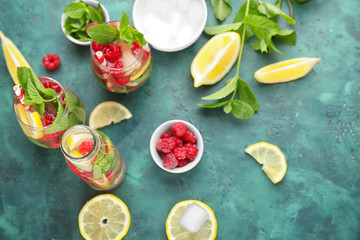 Glasses and bottle of fresh raspberry mojito on green table