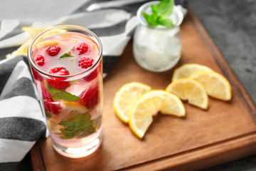 Glass of fresh raspberry mojito on wooden board