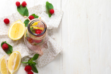 Glass bottle of fresh raspberry mojito on white wooden table