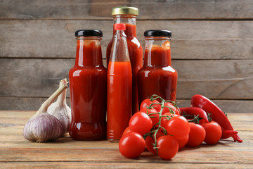 Bottles with tasty tomato sauces and on wooden table