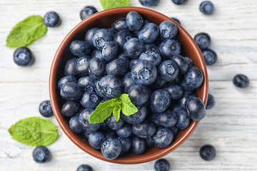 Bowl with ripe blueberries on light table