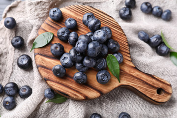 Board with ripe blueberries on table