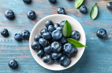 Bowl with ripe blueberries on wooden table