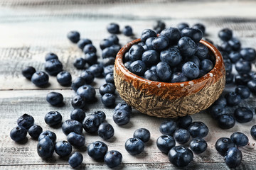 Bowl with ripe blueberries on wooden table