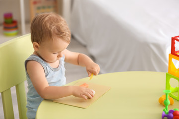 Naklejka premium Cute little boy using play dough at table indoors