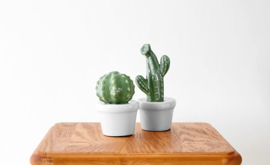 Ceramic cacti in pots on table against white background