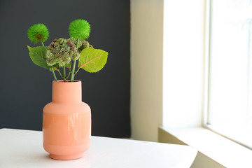 Vase with green plants on white table indoors