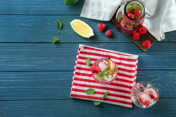 Glasses and bottle of fresh raspberry mojito on wooden table