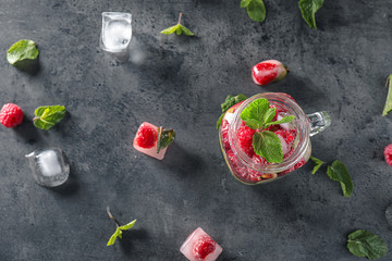 Mason jar of fresh raspberry mojito on dark table