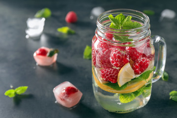 Mason jar of fresh raspberry mojito on dark table