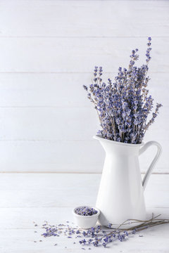 Pitcher with beautiful lavender flowers on white wooden table