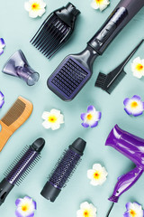 Hairdressing tools with flowers on blue wooden background