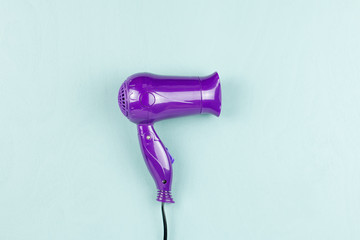 Purple hair dryer on blue wooden background