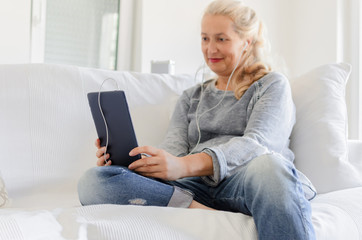 Woman sitting on sofa and holding tablet