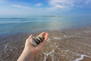 Different color stones in the hand on the background of Baltic sea in summer