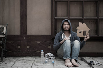 Homeless man showing a cardboard house for help, Dirty man loss home,lowkey image style