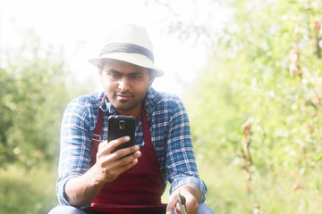 Junger Mann im Obstgarten mit Handy