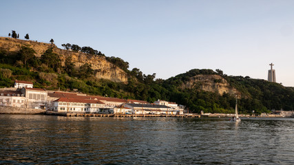 Dilapidated industrial buildings on the River Tagus in Arialva, Lisbon, Portugal, and the Cristo Rei landmark in the distance.