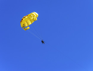 Tourists fly by parachute over the water in sky.