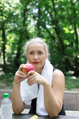Senior woman eating apple in nature