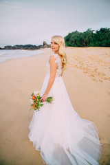 Fototapeta na wymiar young bride is standing on tropical beach