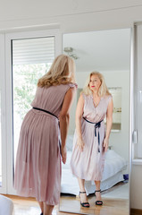 Senior woman standing in dress in front of mirror