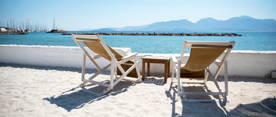 Two Deckchairs In Tropical Beach at quiet sea.