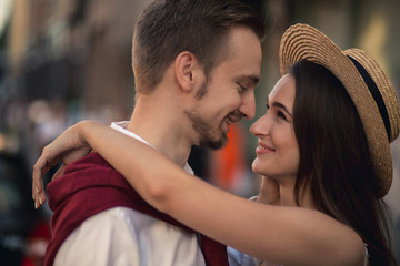 A girl in a straw hat hugs her boyfriend in a white shirt on the street