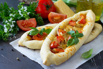 Homemade Greek oval pizza with salami, tomato, onion and cheese.