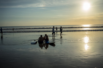 people on beach in water at sunset