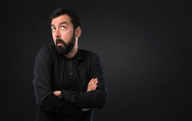 Handsome man with beard making unimportant gesture on black background