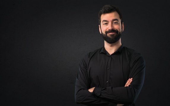 Handsome man with beard with his arms crossed on black background