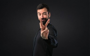 Handsome man with beard making victory gesture on black background