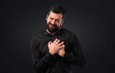 Handsome man with beard with heart pain on black background