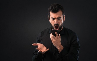 Handsome man with beard talking to mobile on black background