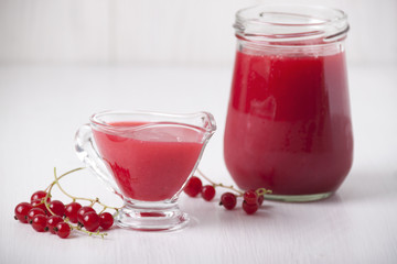 Berry sauce made from red currants in a glass gravyboat and jar