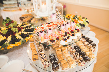 Delicious and tasty dessert table with cupcakes shots at reception closeup
