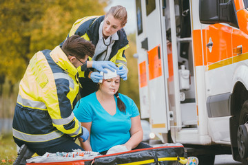 Sanitäter verbinden Kopfwunde von verletzter Frau