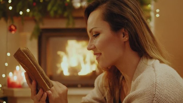 Woman reading book by the cozy fireplace
