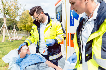 Junge ist nach Unfall verletzt, Sanitäter kümmern sich um ihn