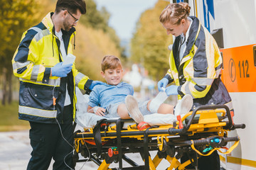 Sanitäter transportieren verletzten Jungen nach Unfall auf Liege