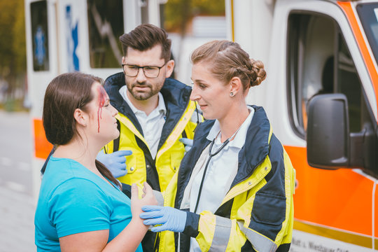 Rettungssanitäter sprechen mit verletzter Frau am Unfallort