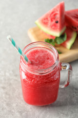 Tasty summer watermelon drink in mason jar on table, closeup