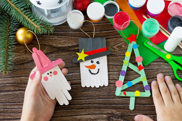 A child is holding Christmas decoration or Christmas gift wooden sticks. Handmade. Project of...